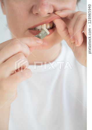 Woman Chewing Nicotine Snus Product.  128965940