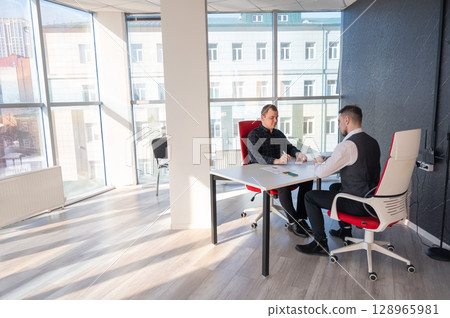 Two Caucasian men communicating at a business meeting. Two Caucasian men communicating at a business meeting. 128965981