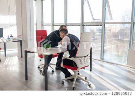 Two Caucasian men communicating at a business meeting.  Two Caucasian men communicating at a business meeting.  128965983
