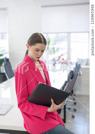 Caucasian business woman reading documents in office. Caucasian business woman reading documents in office. 128965998