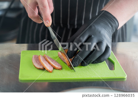 The chef slices the roast duck.  128966035