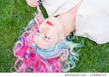 Caucasian woman with colorful hair on green grass. 128966235