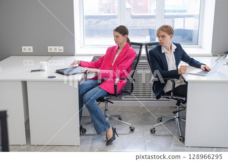 Colleagues communicate while at work in the office. Colleagues communicate while at work in the office. 128966295