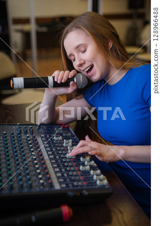 Young woman mixing live sound. Girl recording a song in the studio.  128966488
