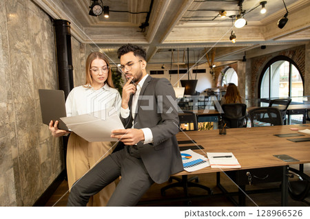 Two young professionals working in the office and looking involved 128966526