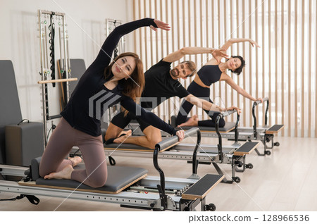 Engaging Group Pilates Session in a Modern Studio Engaging Group Pilates Session in a Modern Studio 128966536