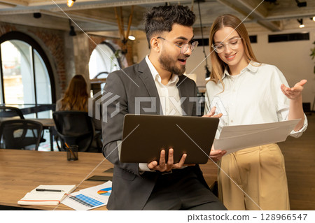 Colleagues in the office discussing project details and looking involved 128966547