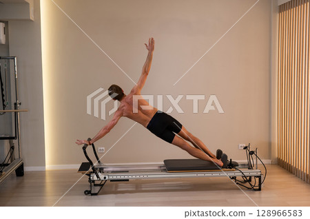 A man doing Pilates on a reformer.  128966583