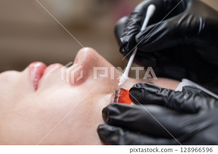 Caucasian woman undergoing eyelash lamination procedure.  128966596