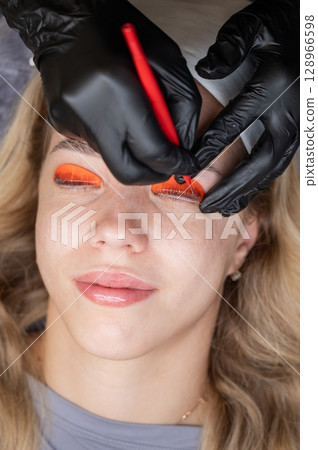 Caucasian woman undergoing eyelash lamination procedure.  128966598