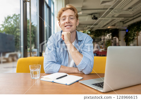 Ginger young man sitting at the table in the cafe 128966615
