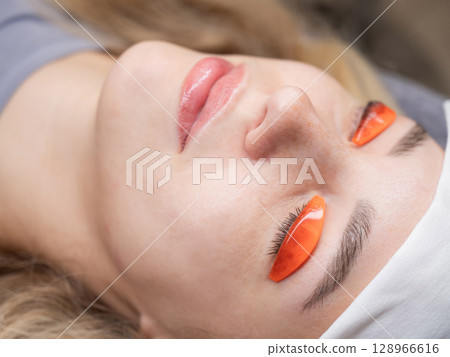 Caucasian woman undergoing eyelash lamination procedure.  128966616