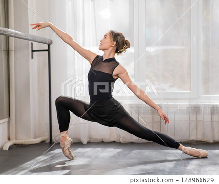 A beautiful Asian woman is dancing at the barre. Ballet dancer. A beautiful Asian woman is dancing at the barre. Ballet dancer. 128966629