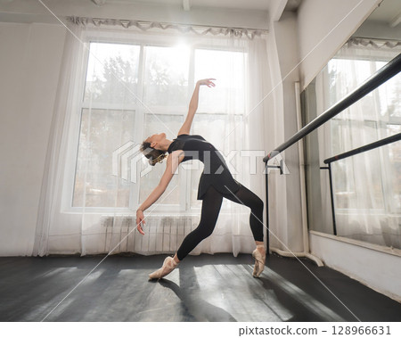 A beautiful Asian woman is dancing at the barre. Ballet dancer. A beautiful Asian woman is dancing at the barre. Ballet dancer. 128966631