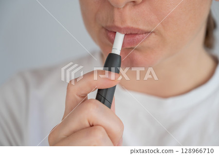 Woman smoking tobacco heating system. Electronic cigarette. 128966710