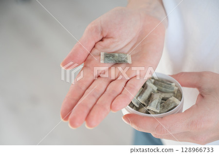 A woman holds a jar of chewing tobacco.  128966733