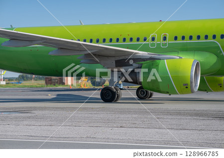 Airplane undergoing repairs in the open air. 128966785