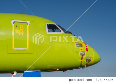 Airplane undergoing repairs in the open air. 128966786