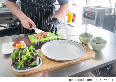 The chef slices the roast duck.  128966803