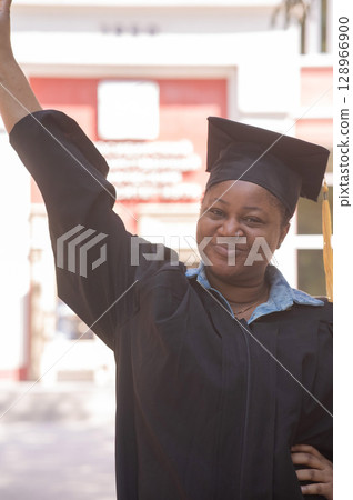 Portrait of happy african woman in graduation gown.  128966900