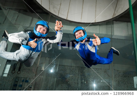 A male instructor teaches a woman how to fly in a wind tunnel. Free fall simulator. 128966968