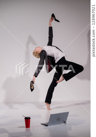 Barefoot ballerina dancing in business suit on white background.  128967021