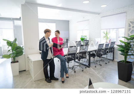 Colleagues look at a folder with documents and discuss work issues.  128967131