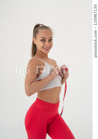 Young woman measuring her chest circumference on white background. 128967139