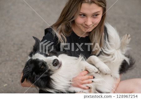Young caucasian woman sitting on asphalt and hugging border collie dog. Young caucasian woman sitting on asphalt and hugging border collie dog. 128967254