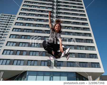 Girl practices skiing tricks on a trampoline.  128967348