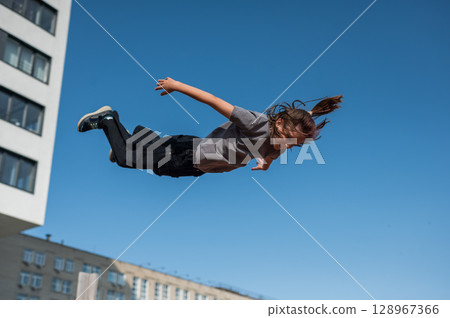 A girl jumps on an outdoor trampoline. 128967366