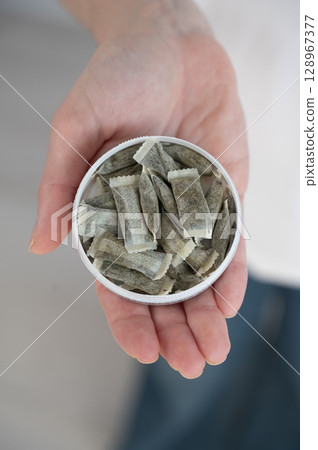 A woman holds a jar of chewing tobacco. A woman holds a jar of chewing tobacco. 128967377