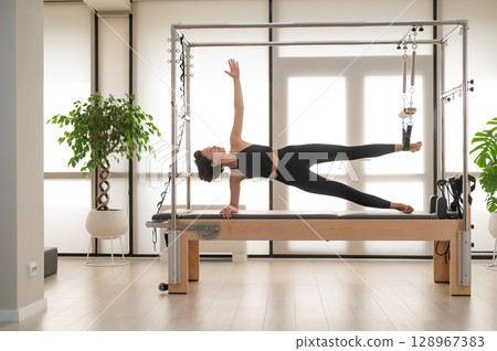 Asian woman doing pilates on reformer.  128967383