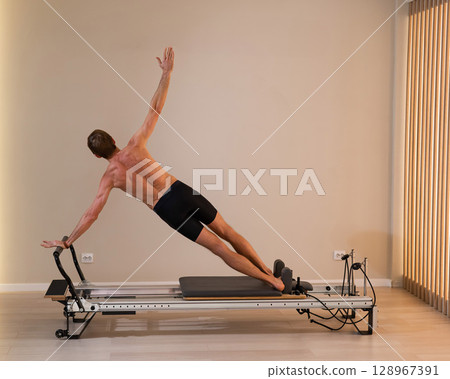 A man doing Pilates on a reformer.  128967391