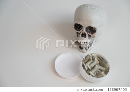 Skull Chewing Tobacco on a White Table. Skull Chewing Tobacco on a White Table. 128967403