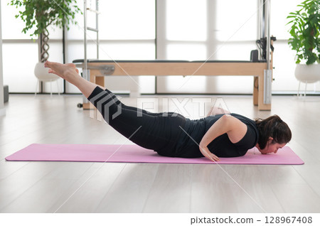 A plump woman does Pilates in a studio. A plump woman does Pilates in a studio. 128967408