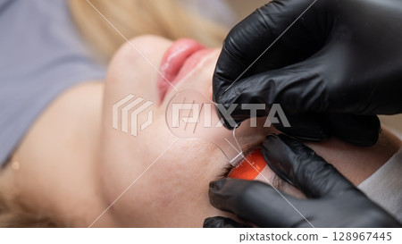 Caucasian woman undergoing eyelash lamination procedure.  128967445
