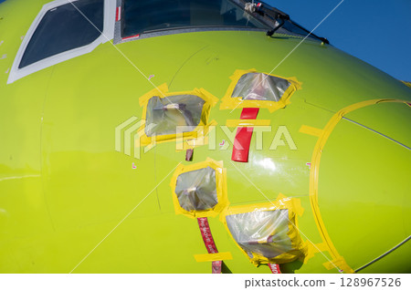 Airplane undergoing repairs in the open air. Airplane undergoing repairs in the open air. 128967526