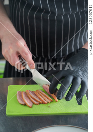 The chef slices the roast duck.  128967612