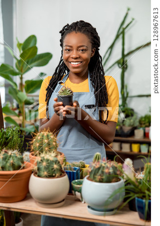 African american cute female flower shop assistant with cactuses 128967613