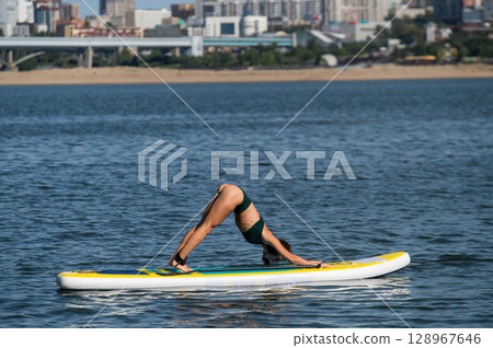 Caucasian woman doing yoga on a SUP board. Caucasian woman doing yoga on a SUP board. 128967646