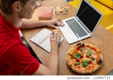 Young man studying in a cafe and looking positive Young man studying in a cafe and looking positive 128967733