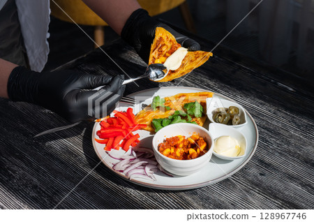 A chef wearing black gloves prepares fajitas. A chef wearing black gloves prepares fajitas. 128967746
