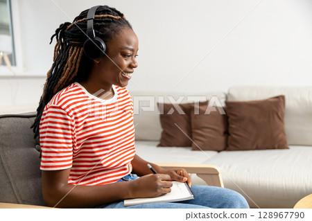 Cute young dark-skinned young woman having online lecture and looking involved Cute young dark-skinned young woman having online lecture and looking involved 128967790