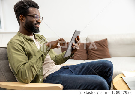 Young man having a video call and looking excited and involved Young man having a video call and looking excited and involved 128967952