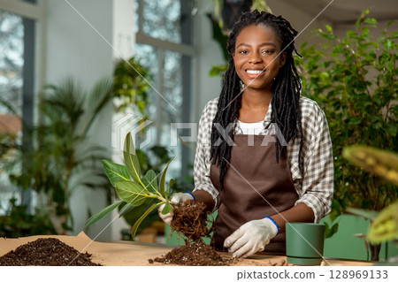 Florist putting soil into the flower pot while planting the flowers Florist putting soil into the flower pot while planting the flowers 128969133