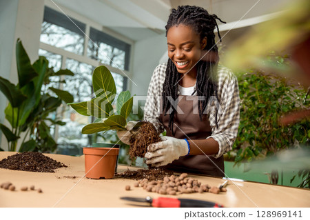 Smiling flower shop assistant planting flowers and feeling good Smiling flower shop assistant planting flowers and feeling good 128969141
