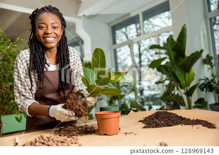 Cute african american florist planting flowers in the flower shop 128969143