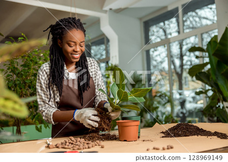 Cute african american florist planting flowers in the flower shop 128969149