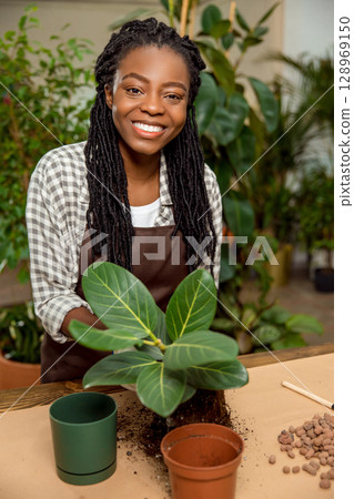 Cute african american florist planting flowers in the flower shop 128969150